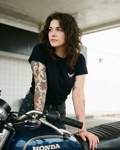 Person with tattoos leaning on a Honda motorcycle indoors