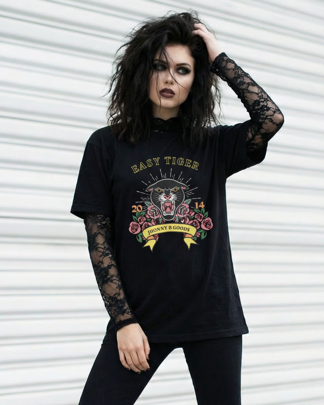 Woman wearing a black graphic t-shirt with long sleeves and black pants in front of a white garage door.