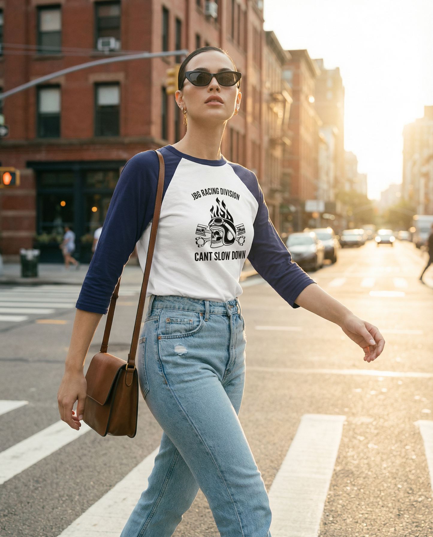 Woman walking on a city street wearing a baseball shirt and sunglasses.
