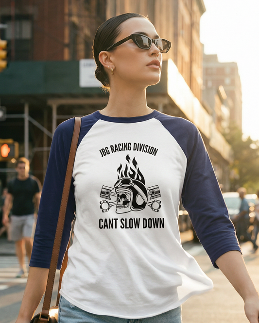Woman walking on a city street wearing a white and blue baseball shirt with text and graphics.