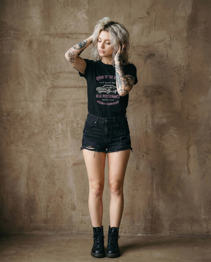 Woman wearing a black t-shirt and denim shorts against a textured brown wall