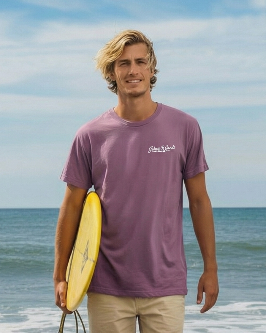 Man holding a surfboard on a beach with ocean and sky in the background
