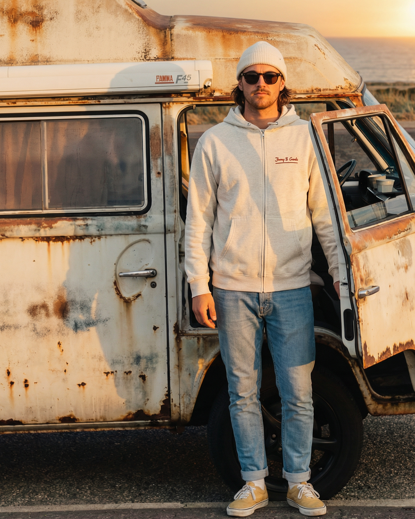 Person standing next to a vintage van by the sea at sunset