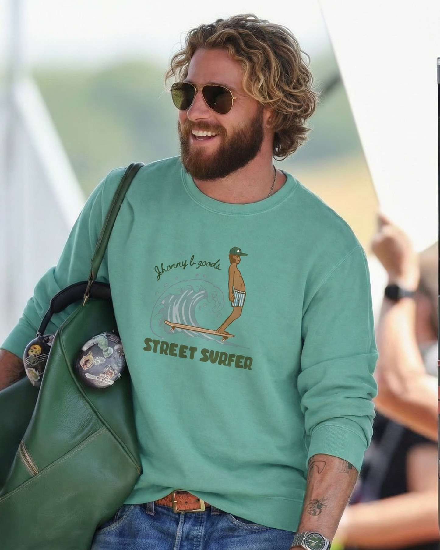 Man wearing a green sweatshirt with a graphic design, standing outdoors.