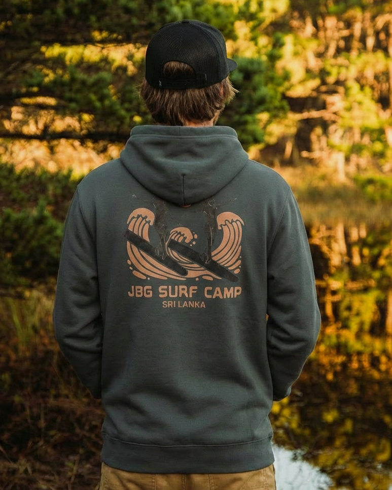Person wearing a hoodie with 'Jog Surf Camp' design in a forest setting