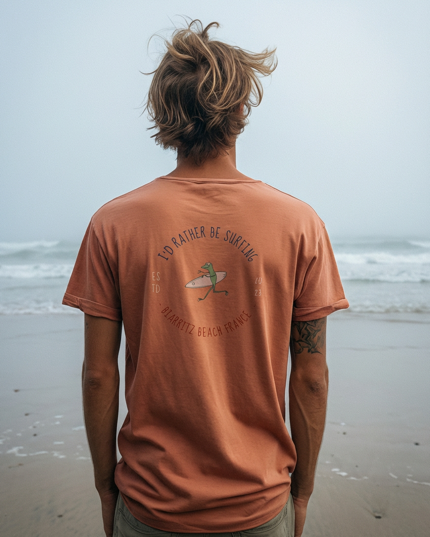 Person wearing a brown t-shirt with a graphic design on a beach