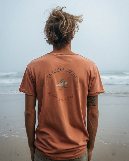Person wearing a brown t-shirt with a graphic design on a beach