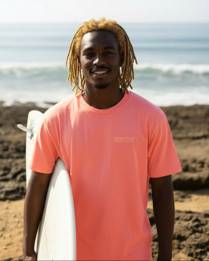 Man with dreadlocks holding a surfboard on a beach