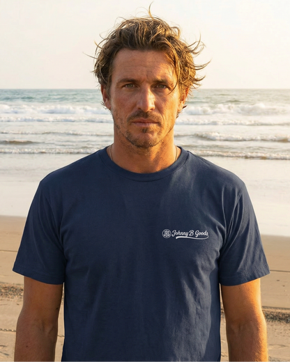 Man wearing a navy blue t-shirt with a logo on a beach