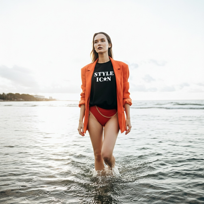 Woman standing in water wearing an orange jacket, black shirt with 'STYLE ICON' text, and red swimsuit.