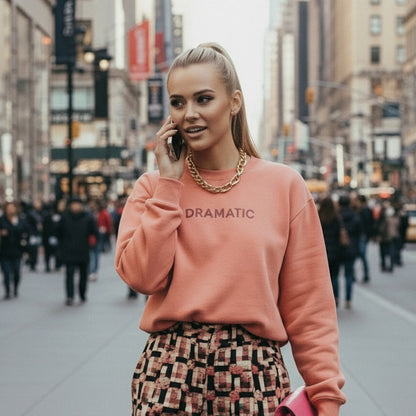 Woman in a pink sweatshirt with 'DRAMATIC' text on a city street