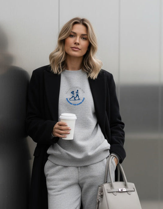 Woman in a stylish outfit holding a coffee cup and a handbag against a modern background