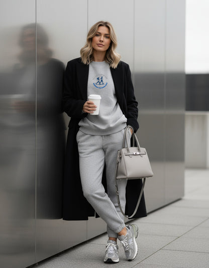 Woman in a stylish outfit holding a coffee cup and a handbag against a modern background