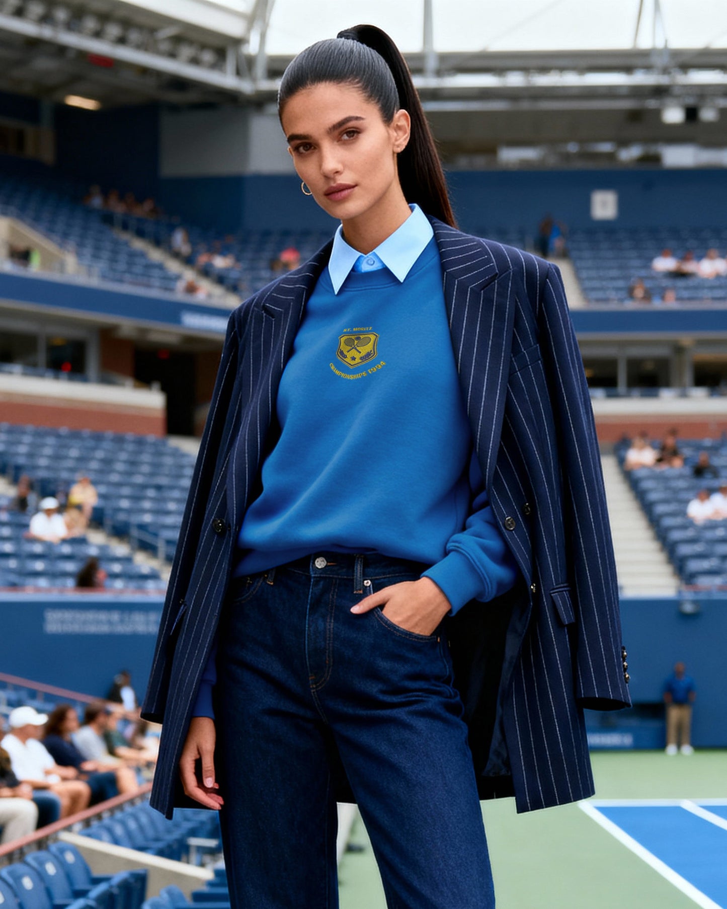 Woman in a blue outfit standing on a tennis court with a stadium in the background