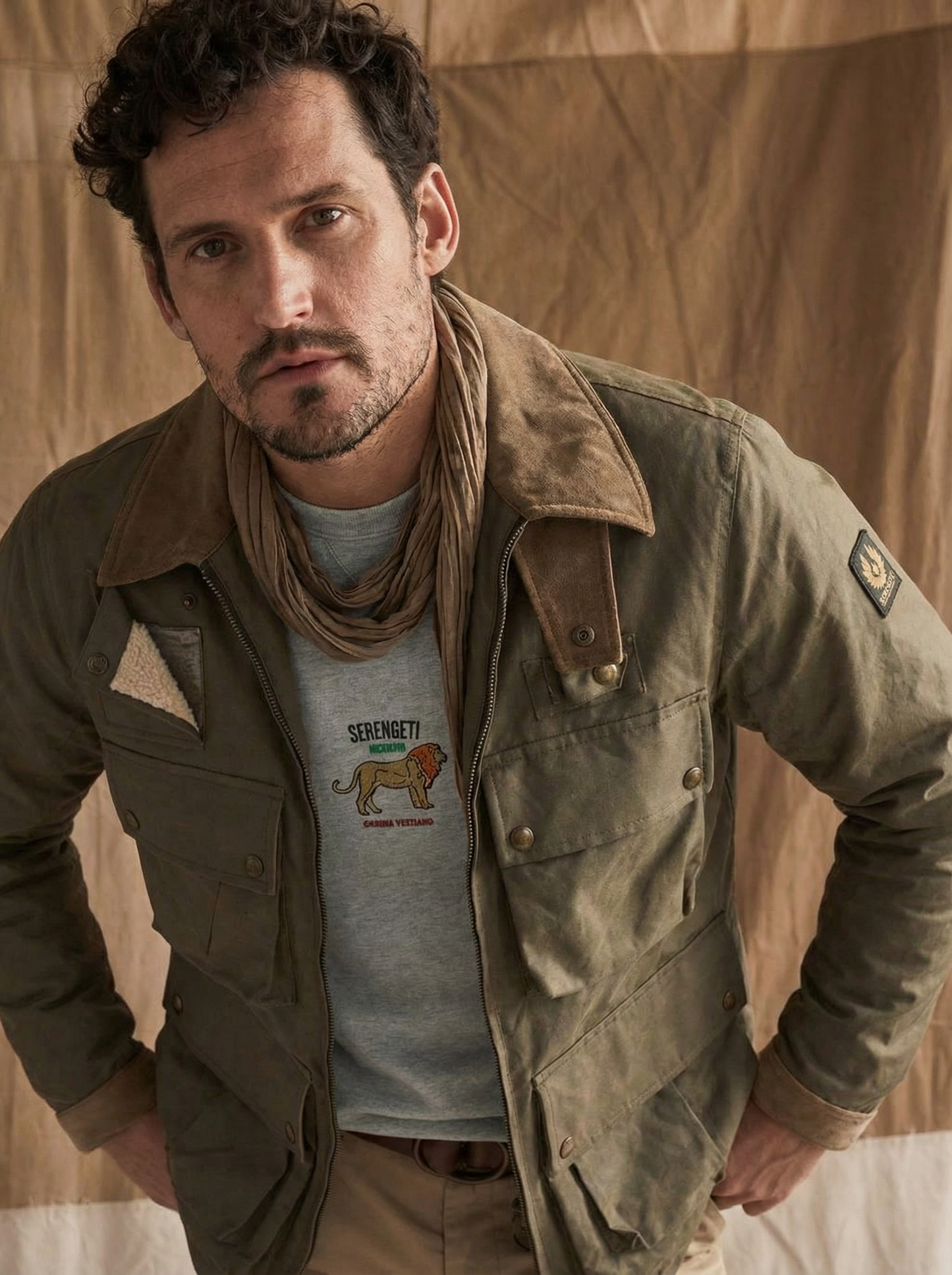Man wearing a brown jacket over a graphic t-shirt with a lion design.