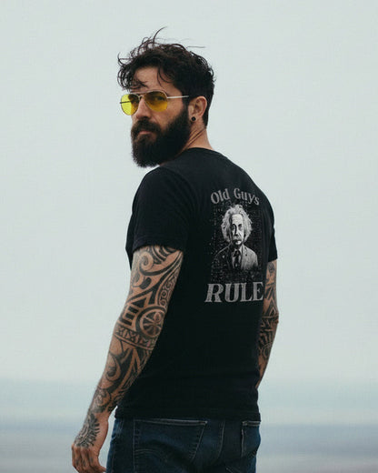 Man wearing a black t-shirt with a graphic design and text, standing against a plain background.