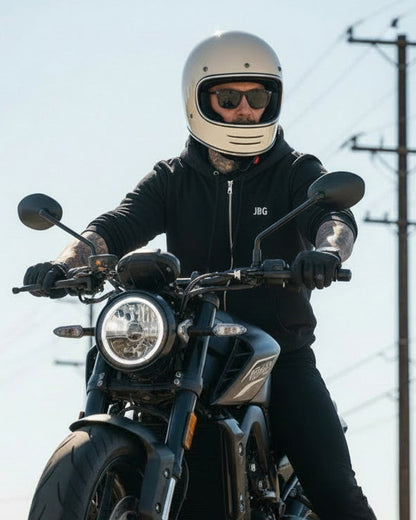 Person riding a motorcycle on a road with power lines in the background