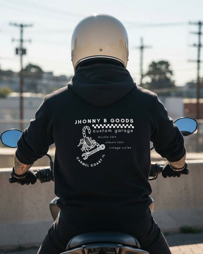 Person wearing a black hoodie with a brand logo, sitting on a motorcycle.