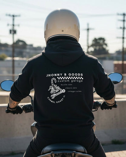 Person wearing a black hoodie with a brand logo, sitting on a motorcycle.