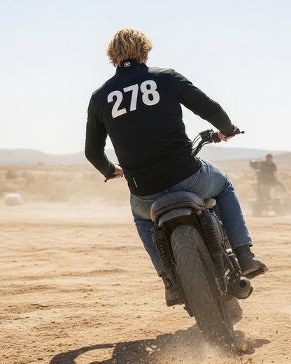 Person riding a motorcycle on a dirt track with another rider in the background