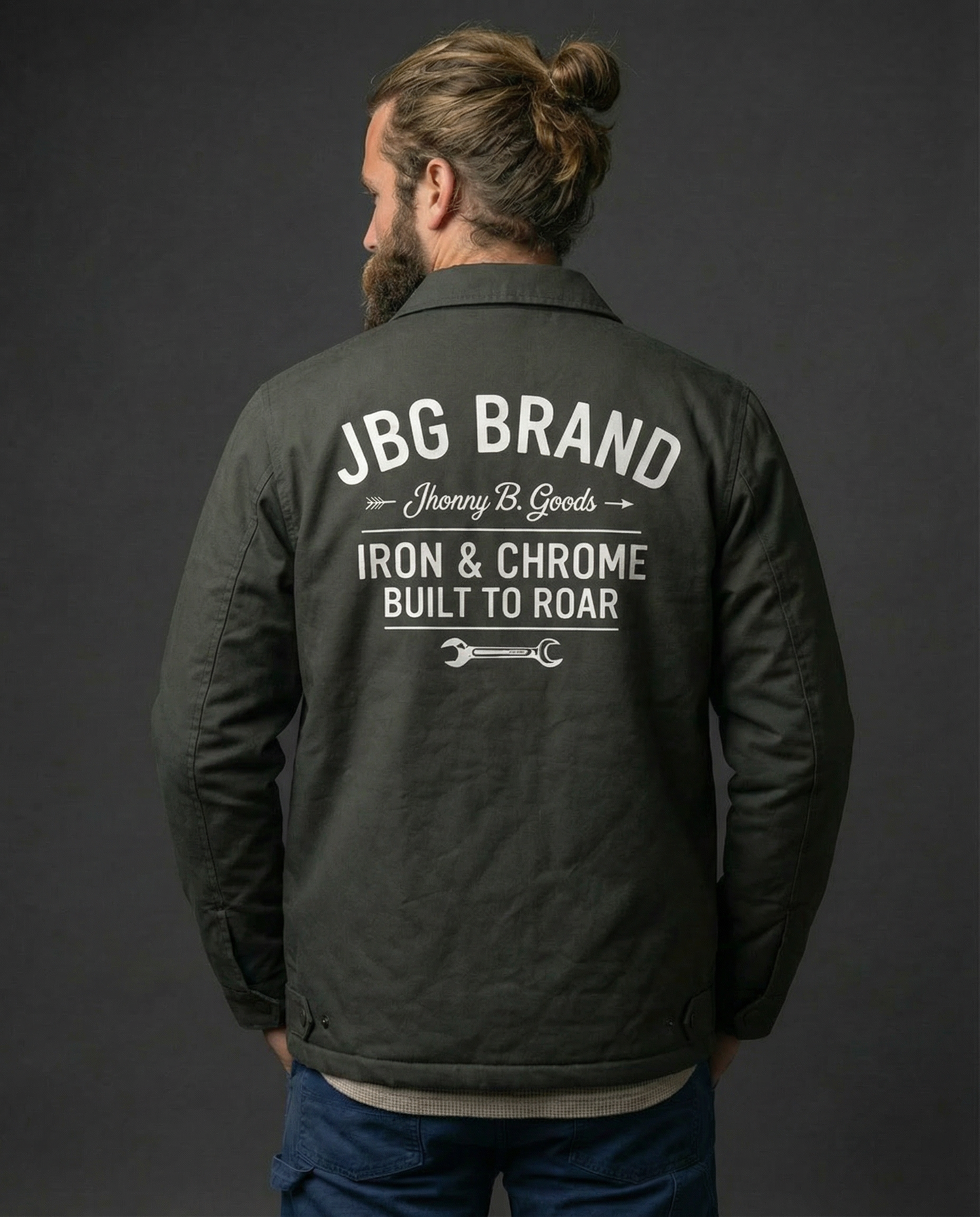 Man wearing a black jacket with 'JBG Brand' text on the back against a dark background