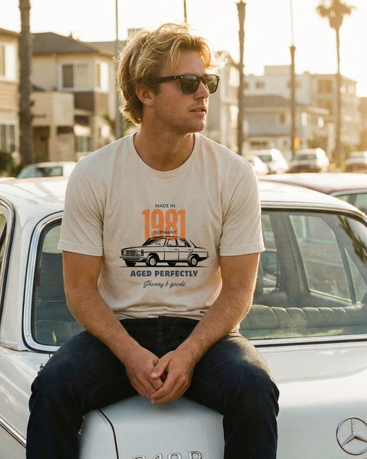 Person sitting on a vintage Mercedes-Benz car with palm trees and buildings in the background