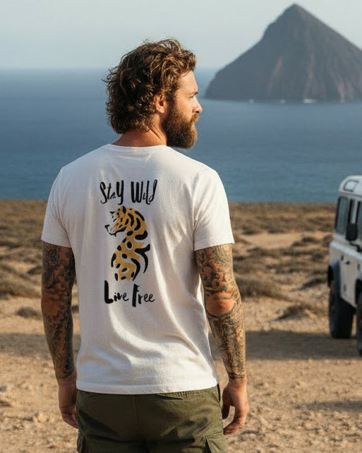 Man standing in a desert landscape with a white truck and island in the background